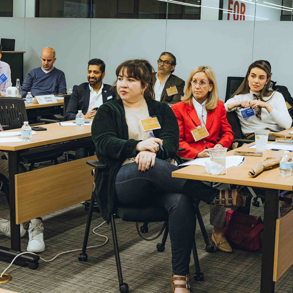 Training participants sit in a Project Cowork training room and listen to a presentation