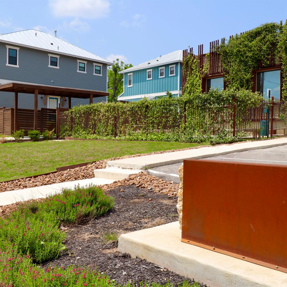 Project Cowork Dignowity exterior - a building with a spacious parking lot, yard, and vines growing up the side