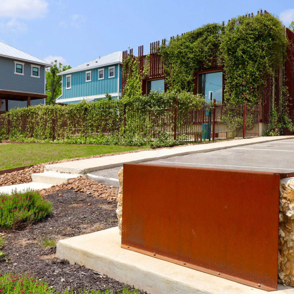 Project Cowork Dignowity exterior - a building with a spacious parking lot, yard, and vines growing up the side